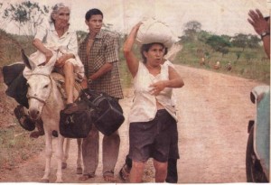 Jairo López acompaña a su abuela María Chamorro para que no se caiga del burro, y su madre Marlene López carga el petate de la ropa en la cabeza.