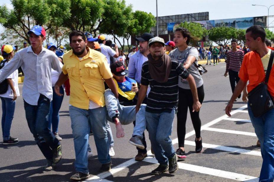 Protestantes socorren a una persona herida durante ataques en Caracas.