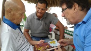 Carlos ´Marrano´Comas observa el libro de la historia del Tolima con Jairo de la Rosa y su hijo Carlos Jr